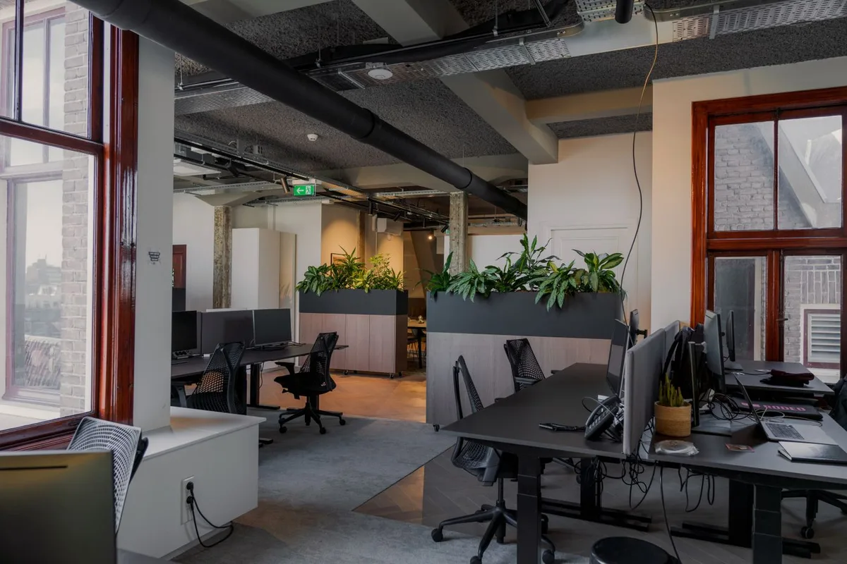 A modern office interior with potted plants placed among the desks